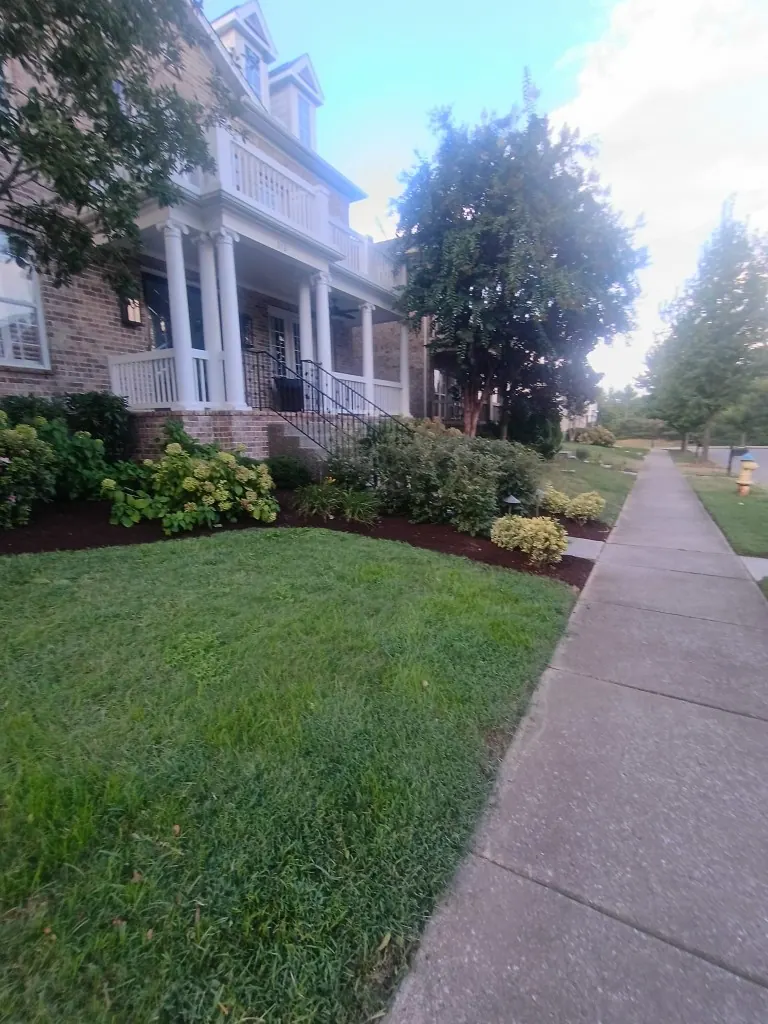 Completed front landscape bed with fresh brown mulch near the porch in Brentwood