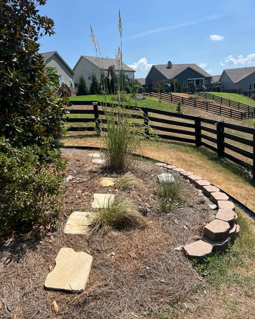 Pine straw landscape bed with sunken stepping stones before pea gravel walkway renovation in College Grove, Tennessee
