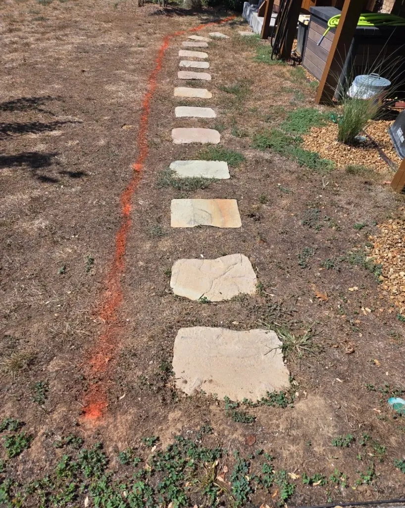 Uneven stepping stones across dry lawn beside a deck before pea gravel walkway installation in College Grove, Tennessee
