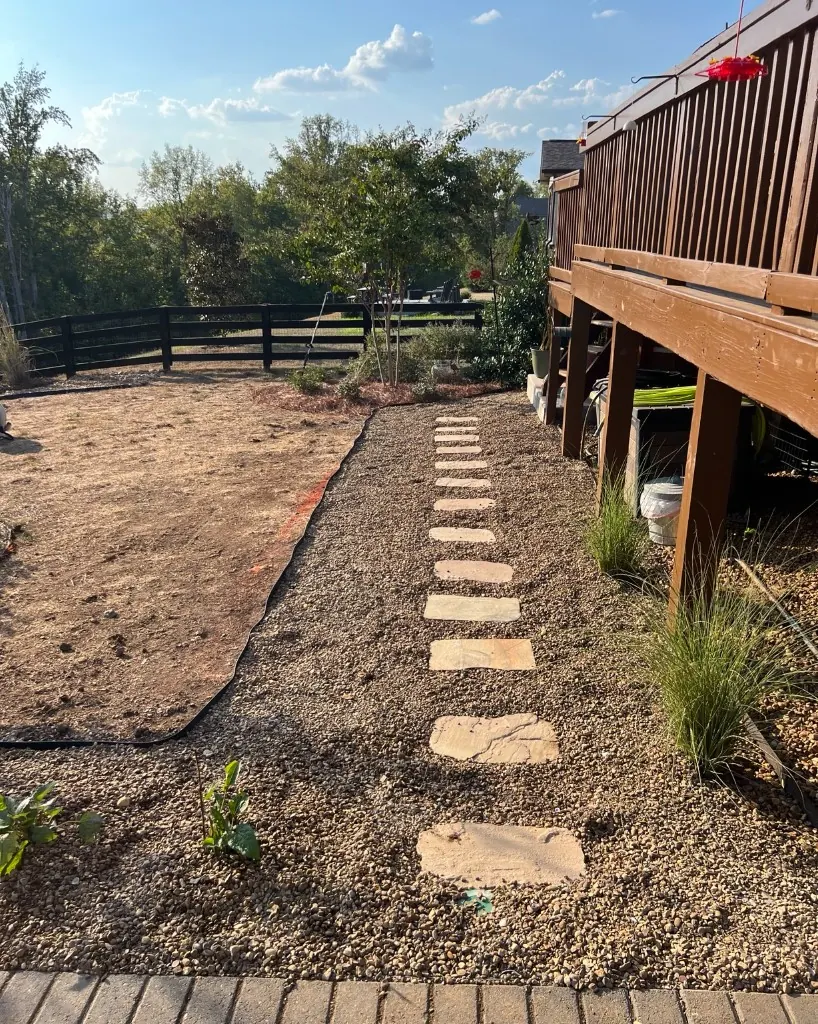 Deck-side pea gravel walkway with straightened stepping stones and landscape edging in College Grove, Tennessee