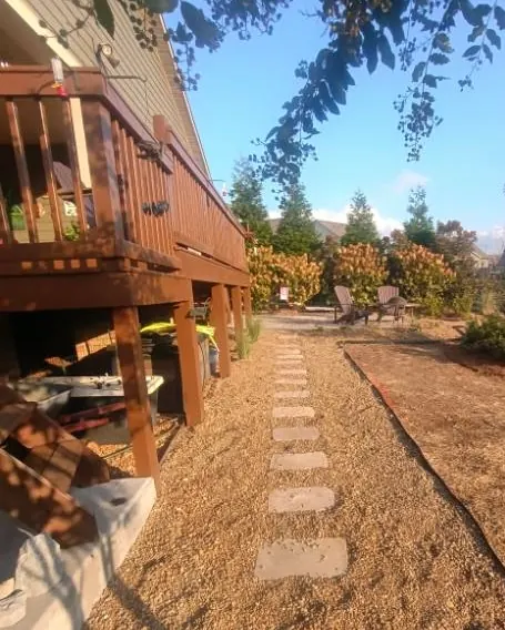 Deck-side pea gravel walkway with stepping stones beside an extended pine straw bed in College Grove, Tennessee