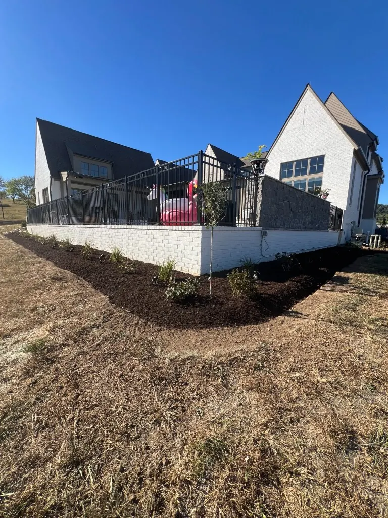 Backyard entrance landscape bed shaped, edged, and finished with brown mulch in College Grove, Tennessee