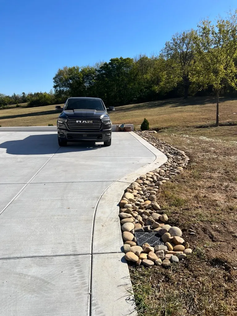 Rock-lined drainage swale with approximately 6 to 8 inch drainage rock beside a driveway in College Grove, Tennessee