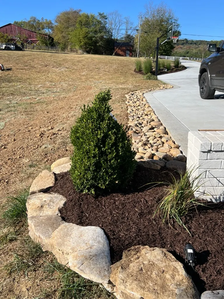 Second angle of the rock-lined drainage swale and adjoining brown mulch bed in College Grove, Tennessee