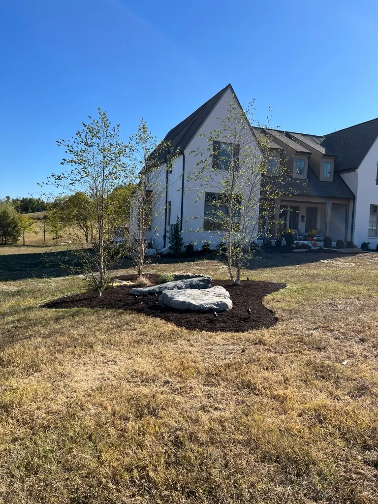 New landscape bed with brown mulch and two large landscape boulders in College Grove, Tennessee