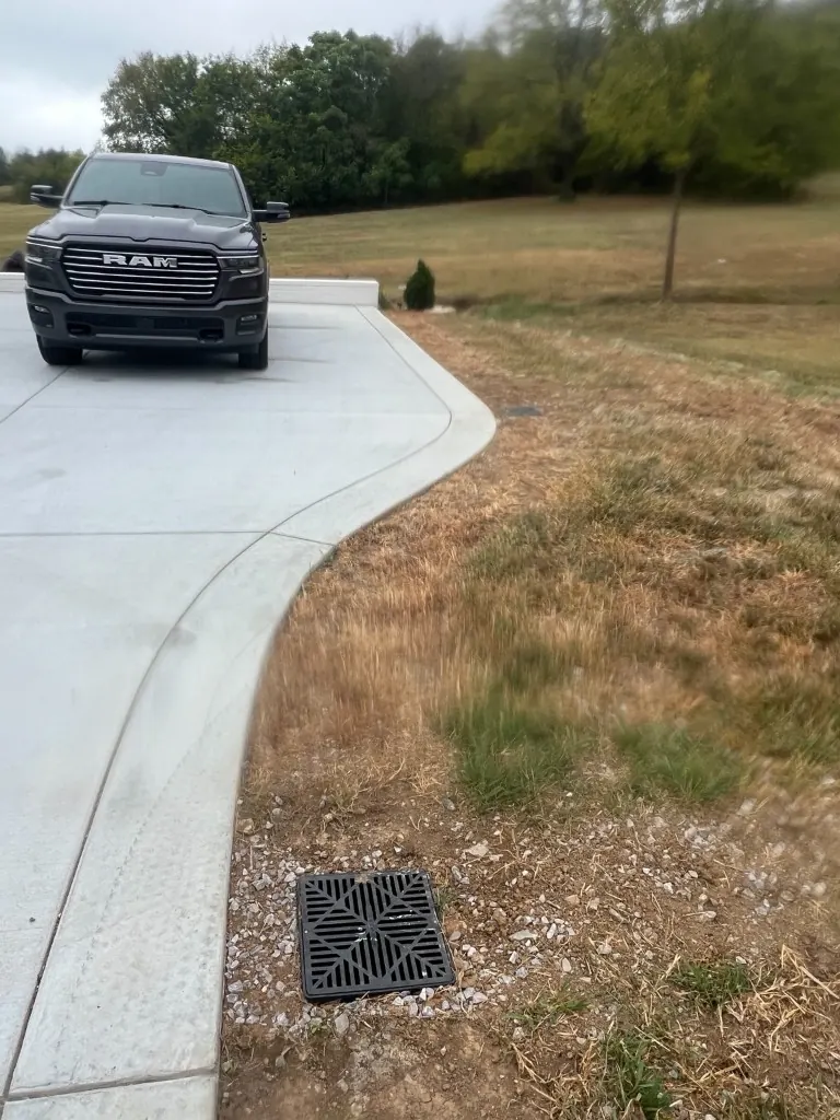 Driveway edge with grass before rock-lined drainage swale installation in College Grove, Tennessee