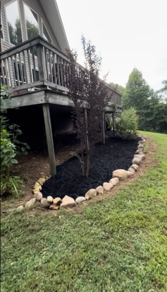 Finished stone-bordered landscape bed with black mulch in Columbia, TN