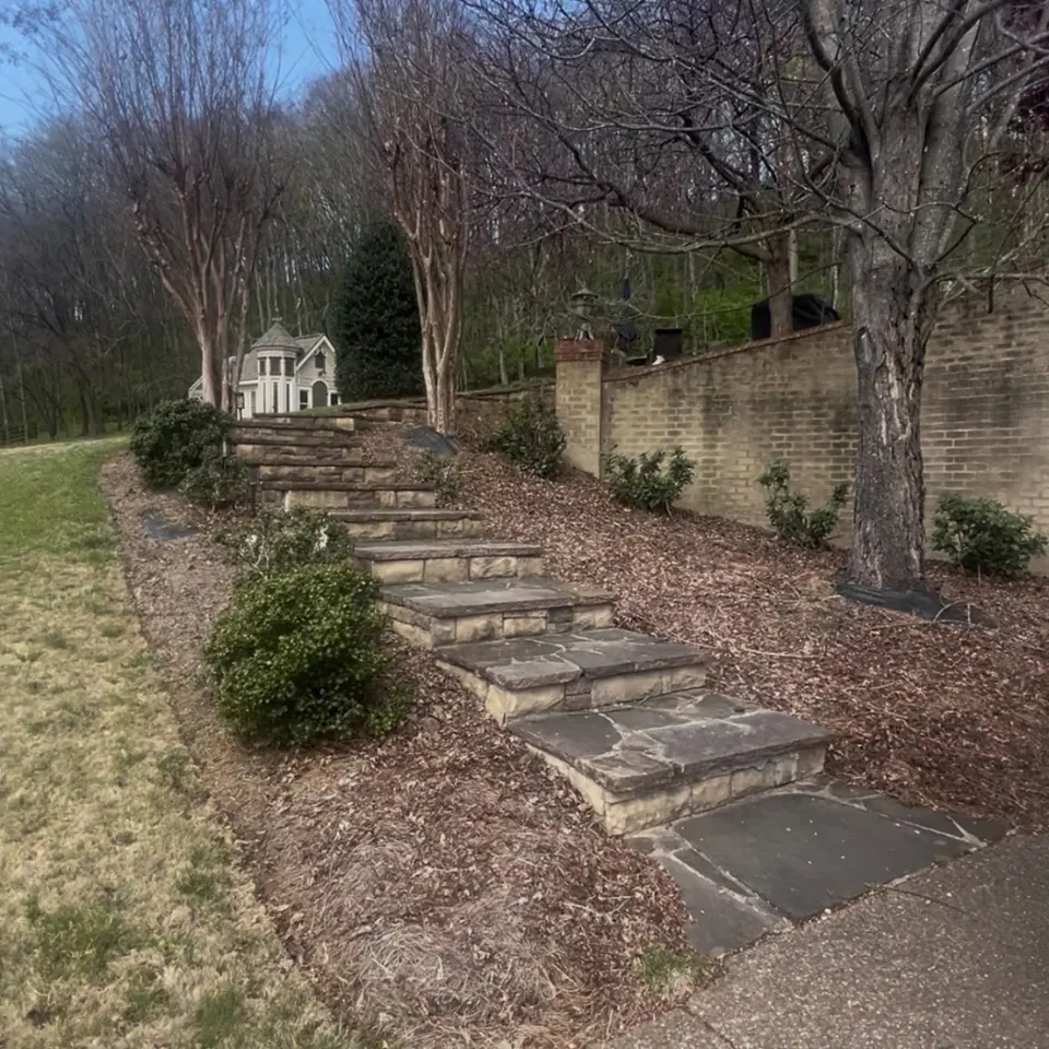 Landscape bed flanking stone stairs before cleanup in Franklin, Tennessee