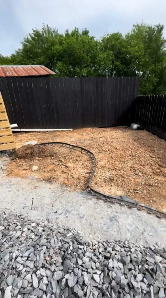Bare unfinished landscape bed area along a black privacy fence before planting and mulch in Spring Hill, Tennessee