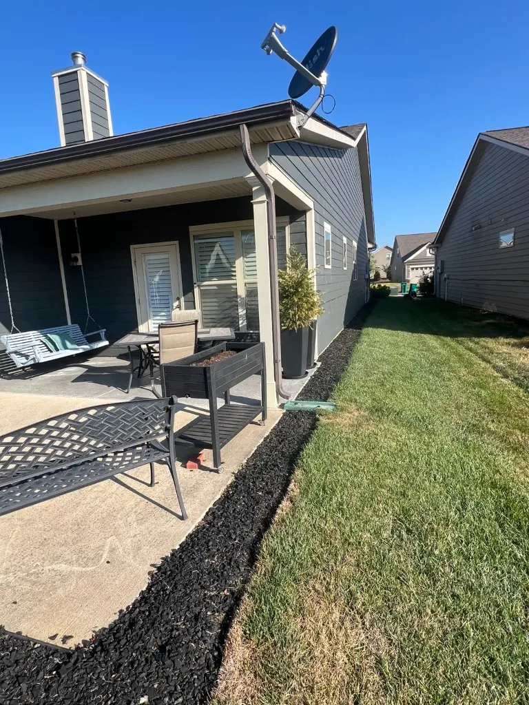 Rear and side patio bed with black rubber mulch before rubber mulch removal in Spring Hill, Tennessee