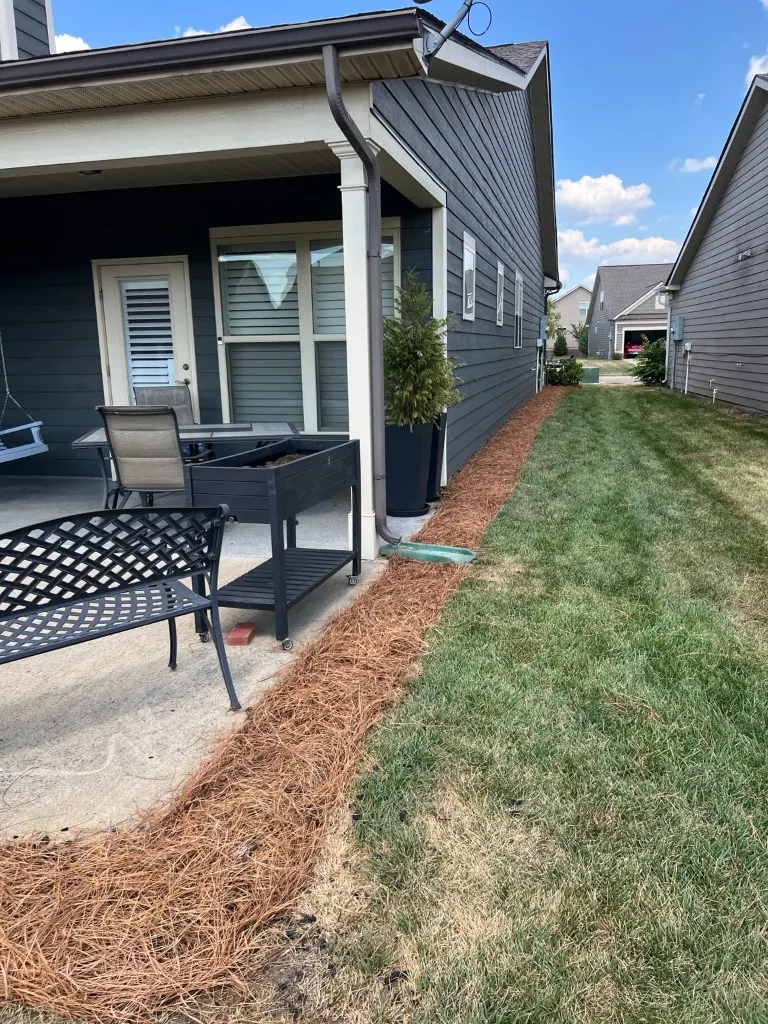 Rear and side patio bed with fresh pine straw and a clean lawn edge after pine straw installation in Spring Hill, Tennessee
